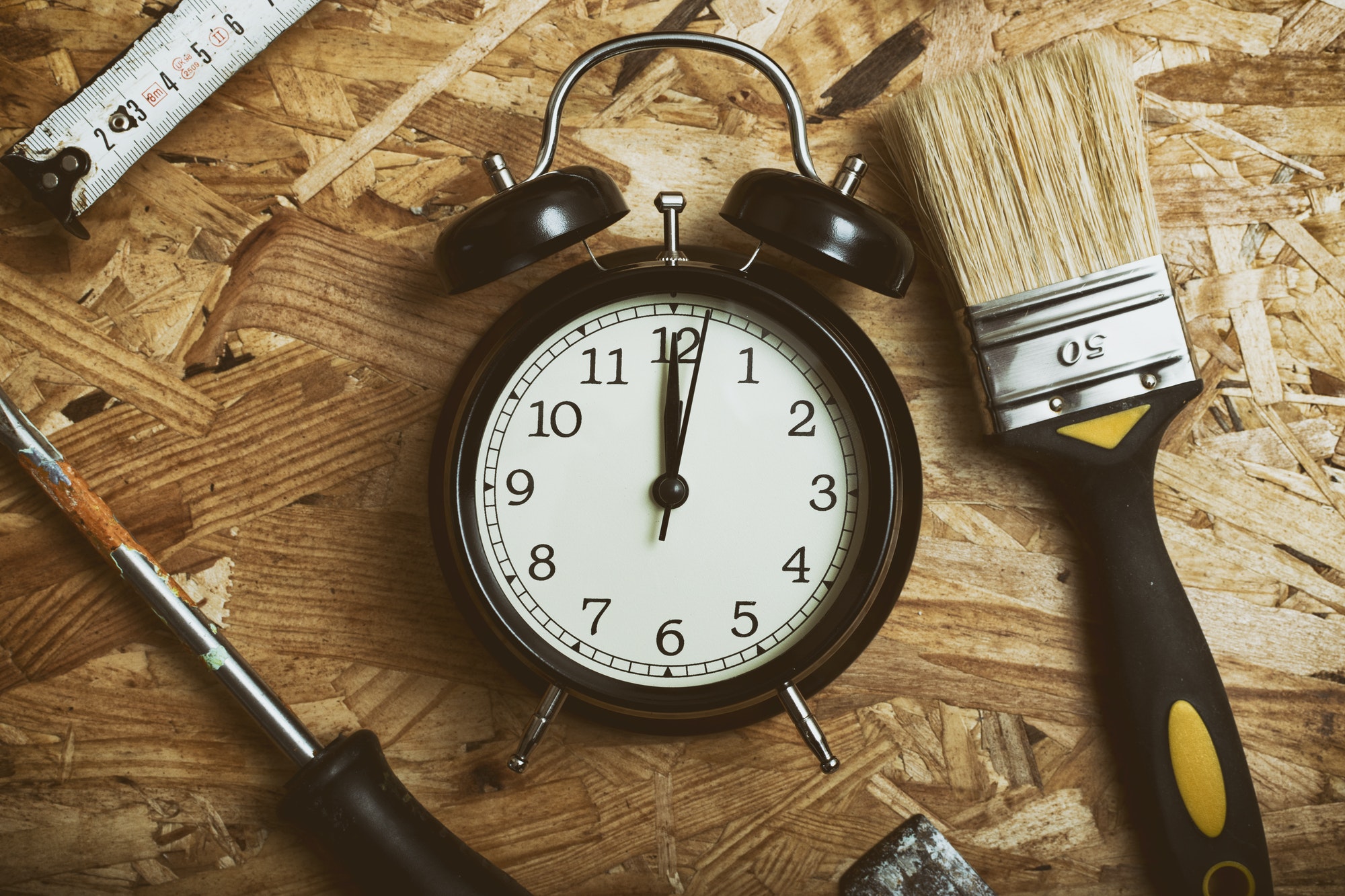 DIY time concept. Tools surrounding a black alarm clock